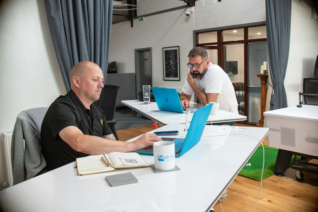 Two men working on laptops in a modern office