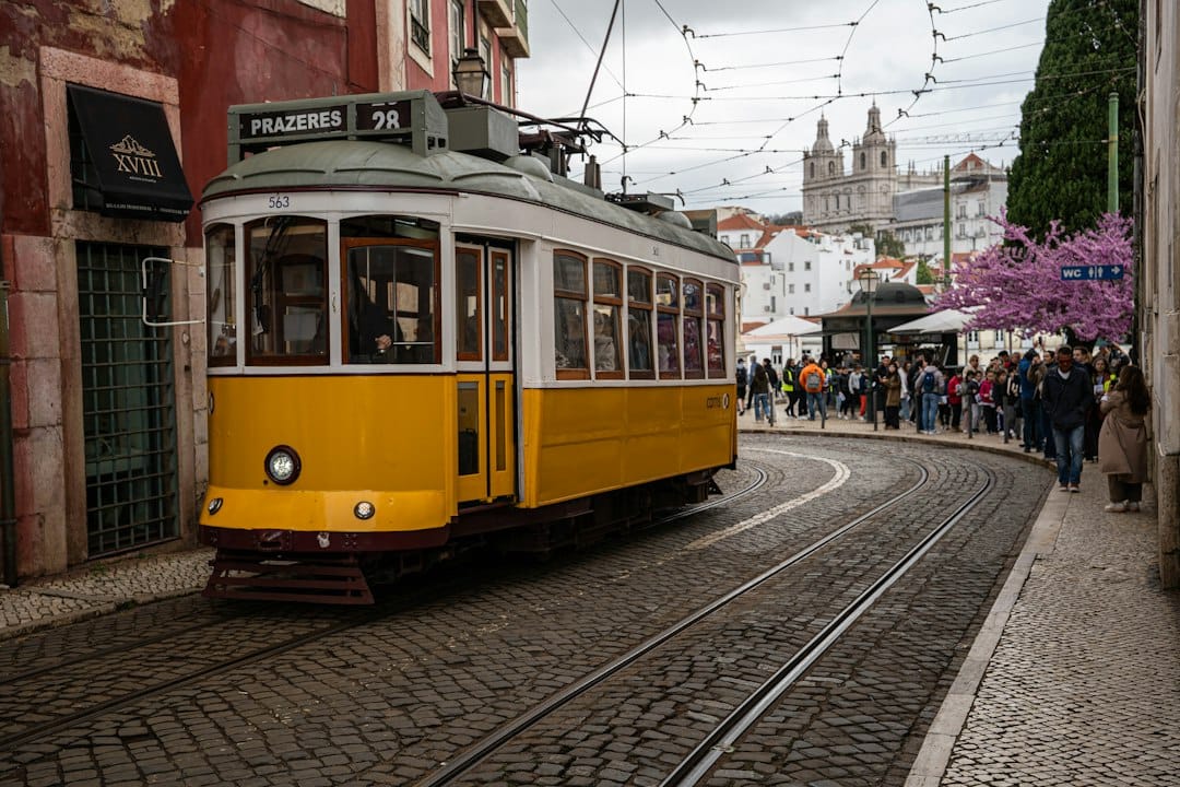 A yellow tram travels down a cobblestone street