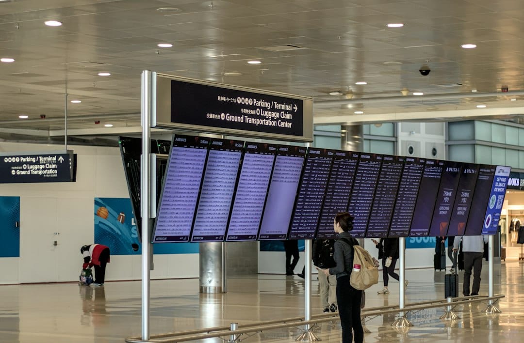 A person with a backpack looking at a large airport flight information display
