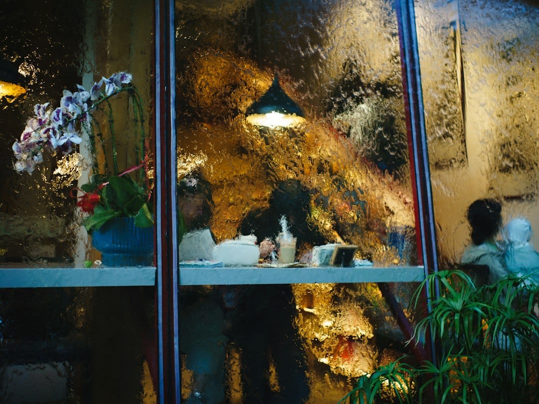 Wet window looking into a cozy, dimly lit cafe