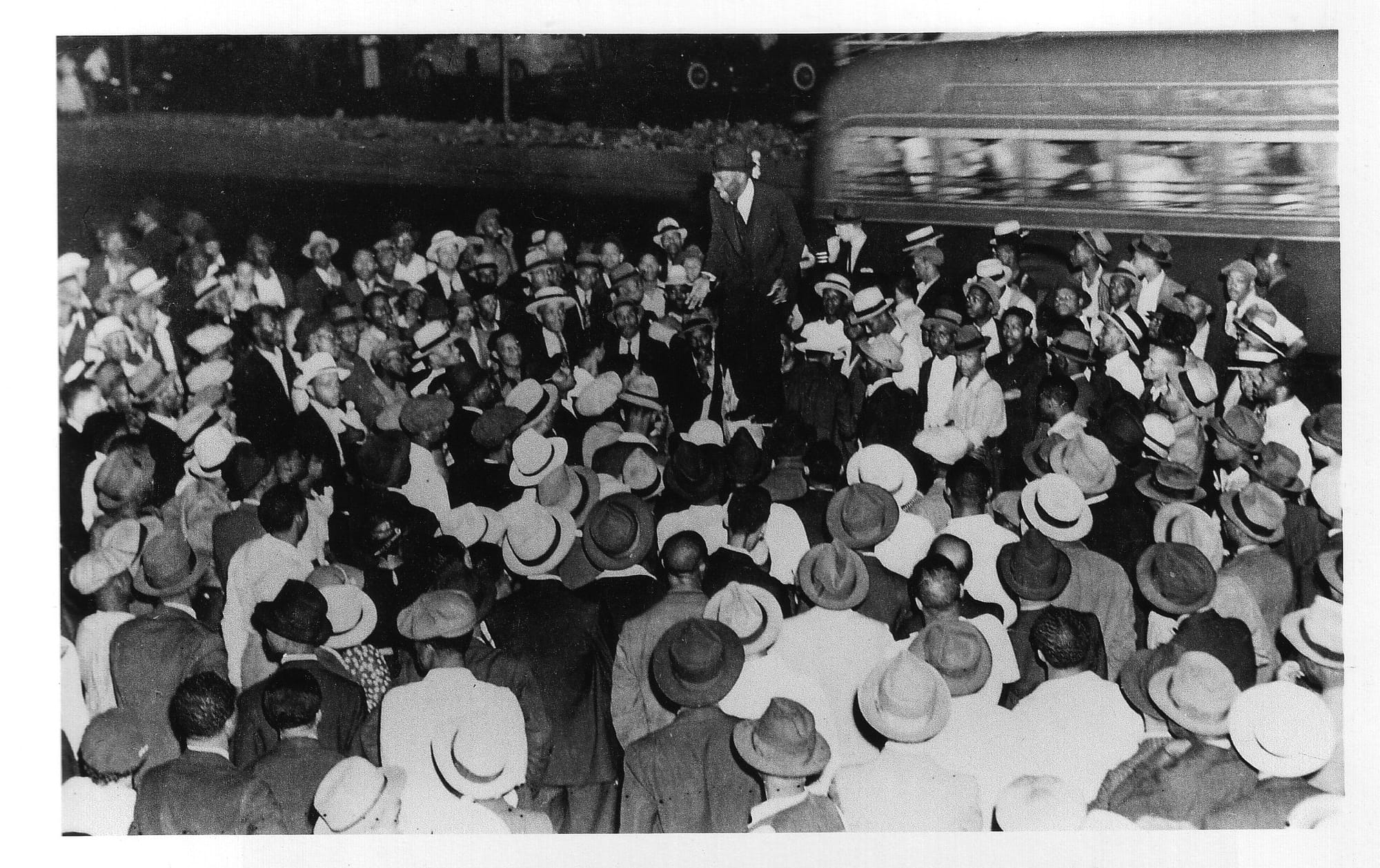 Street corner orator addressing a large crowd in Harlem in 1938, illustrating the tradition of soapbox speaking and public exchange of ideas.