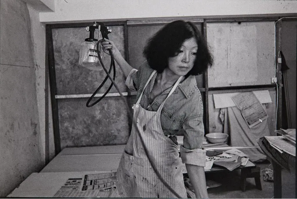 Hai Tien working in her studio, wearing an apron and holding a spray tool.