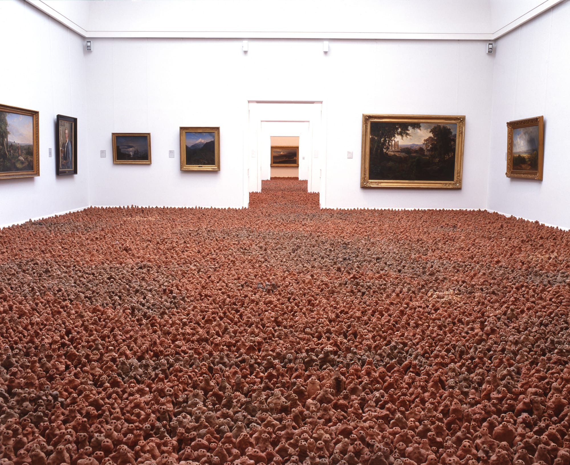 Antony Gormley’s “European Field,” a large-scale installation of thousands of terracotta human figures filling a gallery space, emphasizing collective presence and placement.