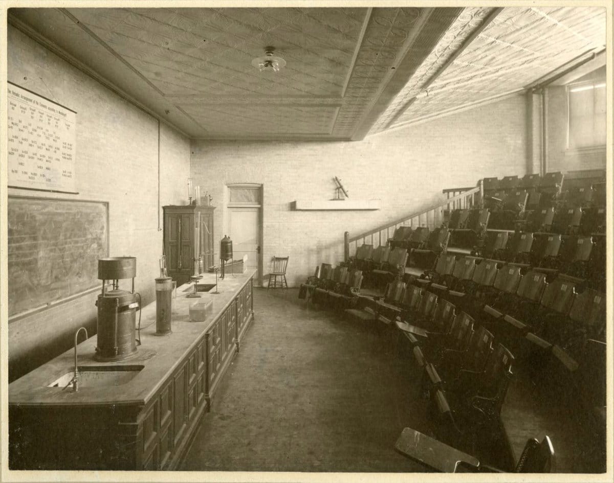 Empty early twentieth-century lecture hall, symbolizing authority and position existing before an audience or recognition.