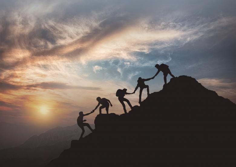 Person standing on mountain summit symbolizing thinking big and achieving ambitious goals