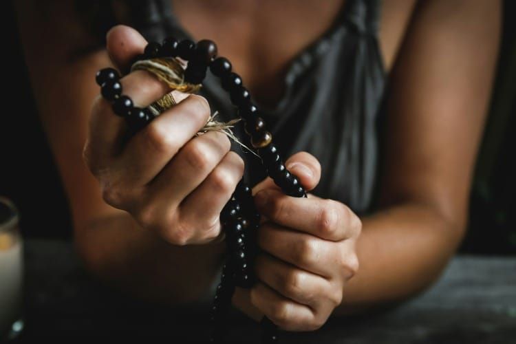 Woman in her 30s holding a black japamala, symbolizing silent mantra practice and deep subconscious alignment through sacred repetition.