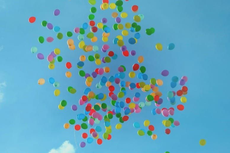 Colorful balloons floating freely in the open sky symbolizing the law of non-attachment, letting go, emotional freedom, and effortless manifestation