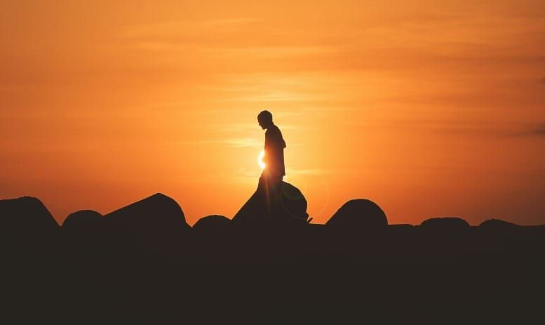 Solo person walking down a mountain at sunset representing self-concept and identity shift in the law of assumption