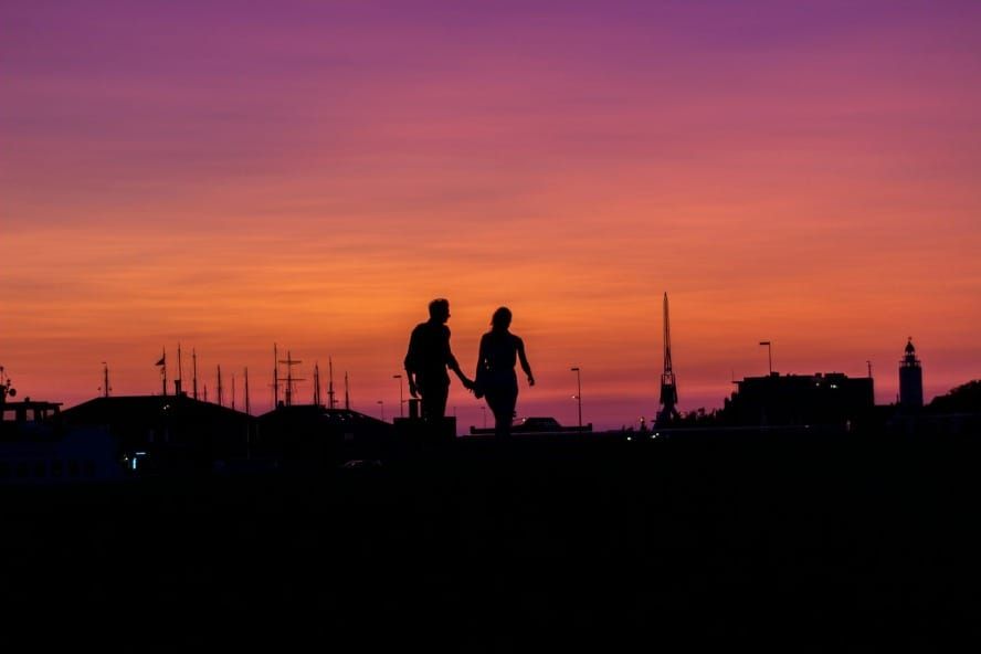 Pareja caminando hacia el atardecer encarnando vivir en el final según las enseñanzas de Neville Goddard