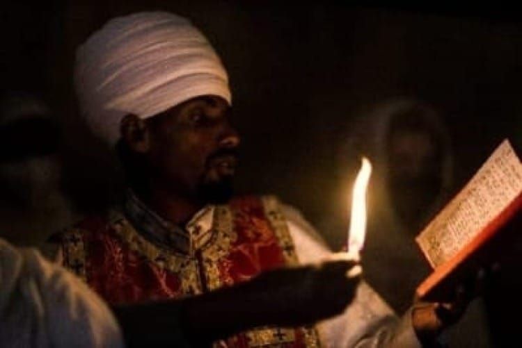 Hombre con turbante blanco leyendo un libro a la luz de una vela, evocando a Abdullah, el mentor místico etíope de Neville Goddard.