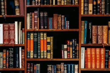 Stack of old library books symbolizing Neville Goddard’s timeless teachings in The Ultimate Guide to manifestation.