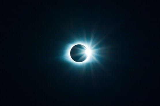 Symbolic image of a dark moon with the rising sun glowing from behind, representing Abraham Hicks’ Step 3—allowing light to emerge after asking and receiving.