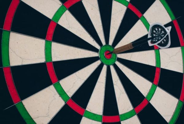 Close-up of a green, red, white, and black dartboard bullseye representing focus, intention, and Law of Attraction alignment for The Game of Life and How to Play It manifestation blog