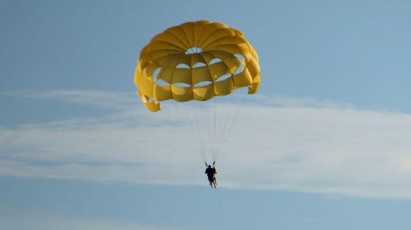 person taking a leap with a yellow parachute symbolizing inspired action and aligned movement in the Law of Attraction
