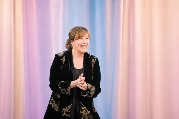 Esther Hicks on stage with soft pastel lavender, blue, and pink curtain backdrop for an Abraham Hicks quotes library on alignment and the Vortex