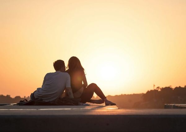 Couple sitting together facing the sunset — manifesting their relationship through Neville Goddard's Law of Assumption and self-concept work