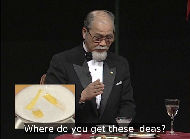 A screencap from Iron Chef. Rosanjin scholar Masaaki Hirano is gesturing as a dish, and is captioned saying "Where do you get these ideas?"