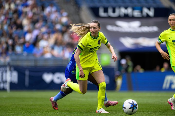 The Washington Spirit's Gabby Carle looks upfield while pursued by a Seattle Reign player.