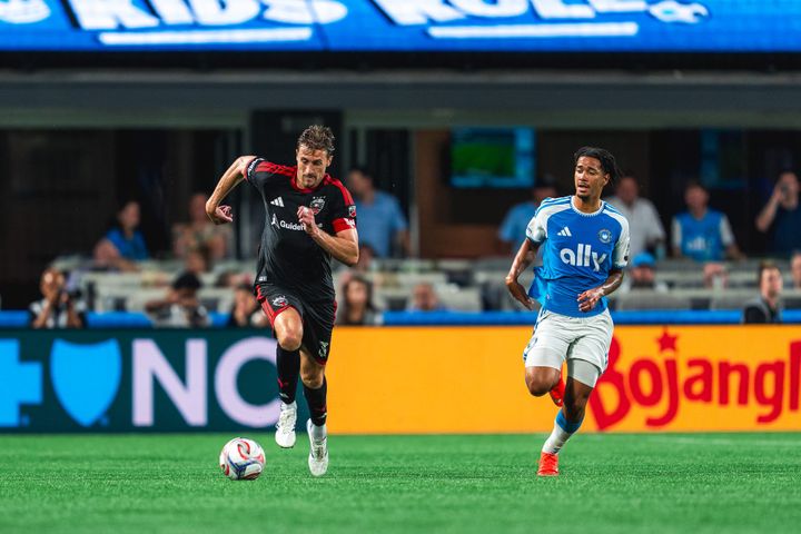 Lucas Bartlett dribbles away from Idan Toklomati during D.C. United's game at Charlotte FC.