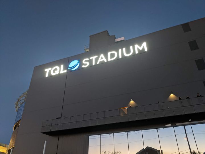 A view of the outside of TQL Stadium, with the stadium name in lights on the facade.
