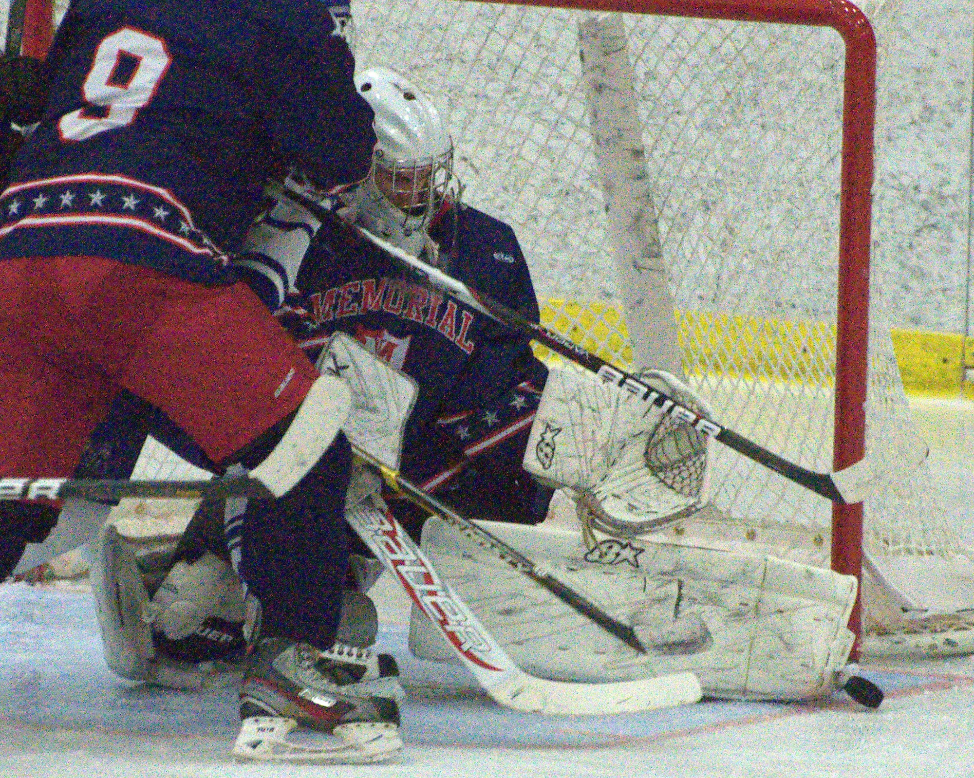 Memorial goalie Aaron Nicolas makes a save just before getting run over by a group of players.