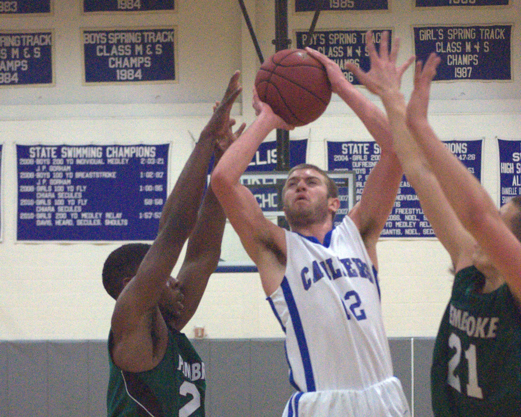 Hollis Brookline's Cole Gallant drives to the basketball between Pembroke's Kafani Williams, left, and Dominic Timbas on Tuesday.