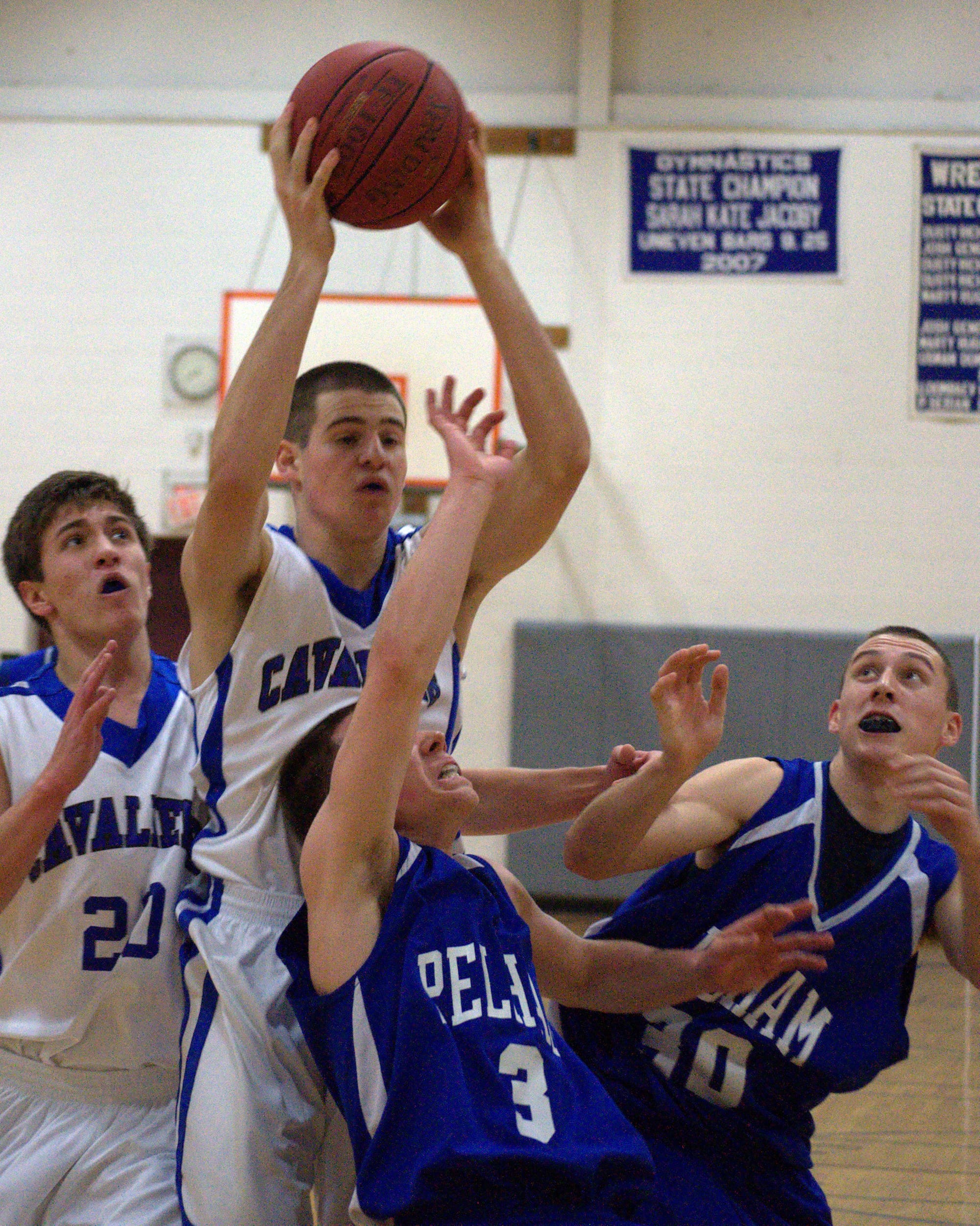 Hollis Brookline's Logan Blake grabs a rebound over Pelham's Joe Slattery during Tuesday's game. For more photos, go to the Photo Album.