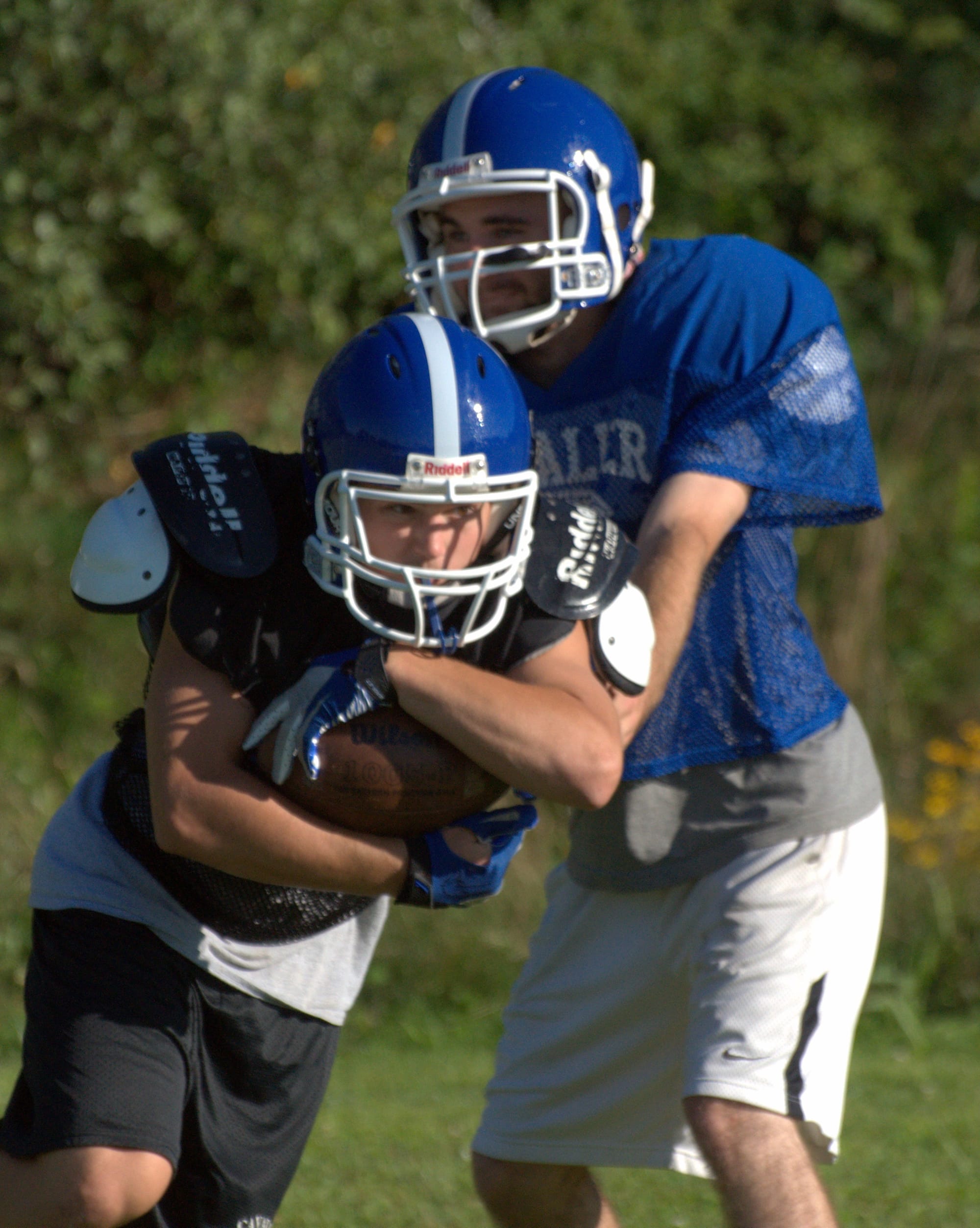 Hollis Brookline's Austin Pigott hands the ball off to Wyatt Farwell during a drill.