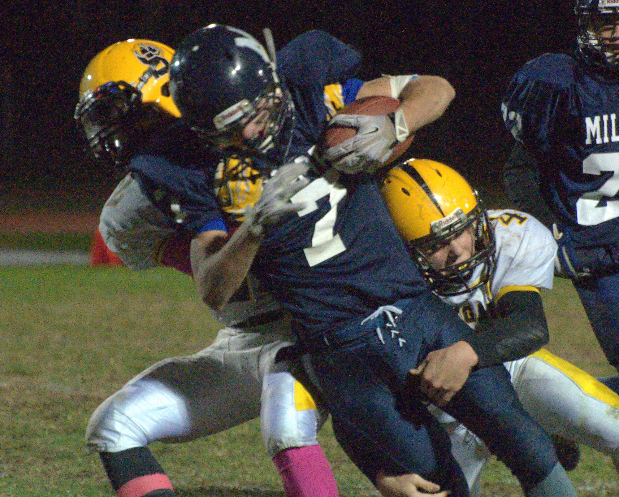 Milford's Mitchell Banuskevich is wrapped up by Souhegan's Will Hart, right, and Zach Bossi during Friday's game.