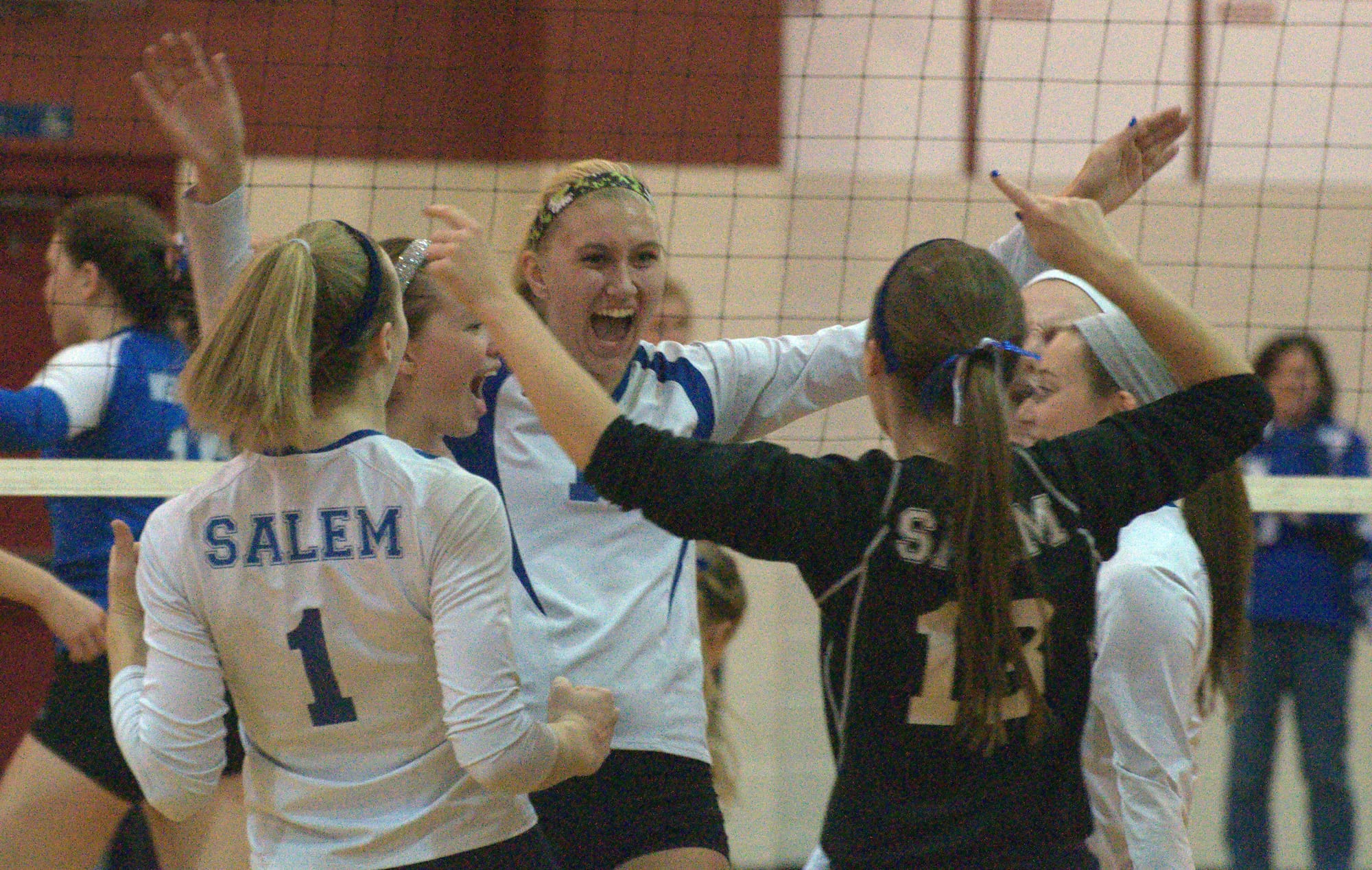 Olivia Burke, center, and the Salem volleyball team celebrate during their semifinal match against Merrimack.