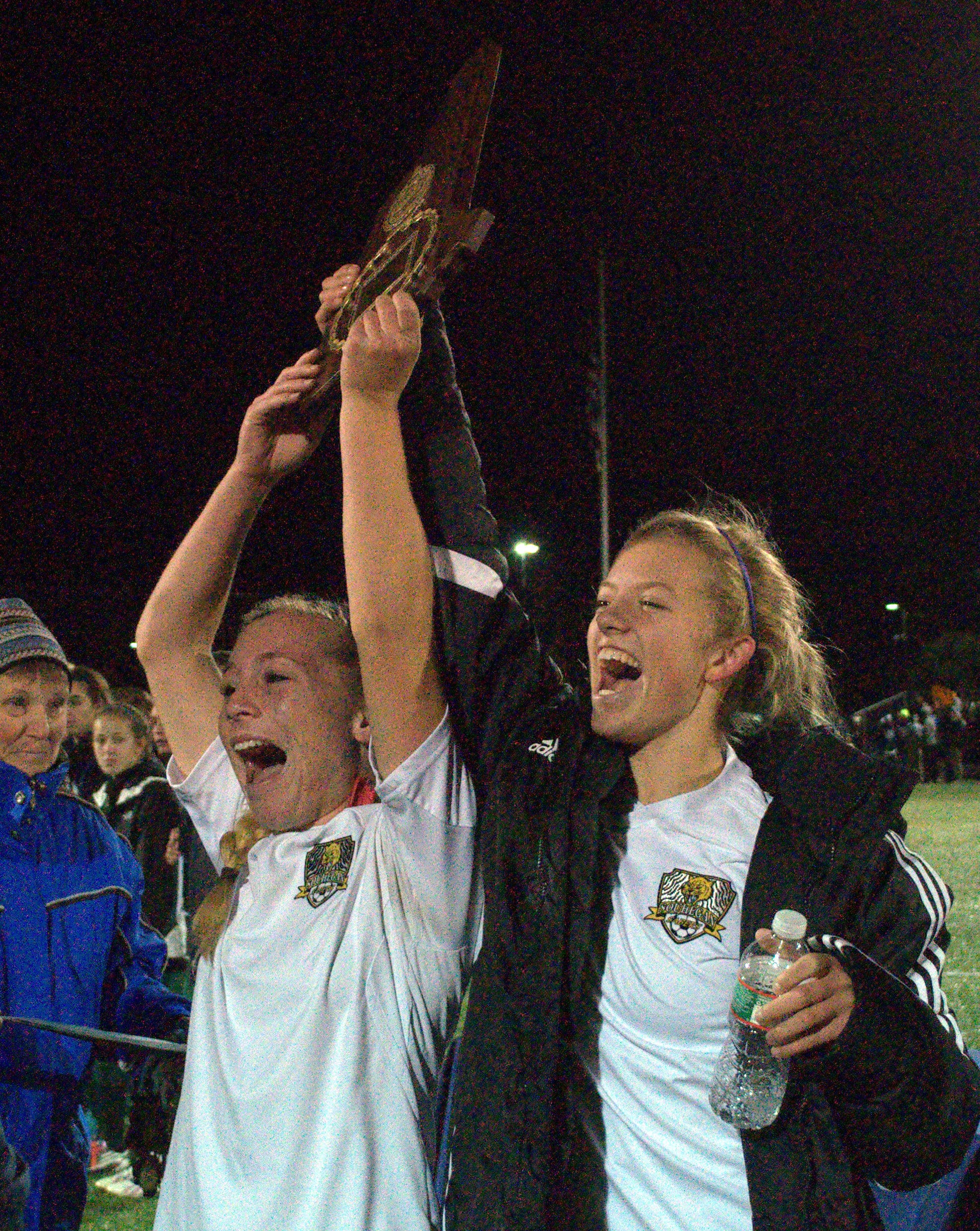 Souhegan's Taylor Behn, left, and Peyton Kent hold up the Division II girls soccer championship plaque.