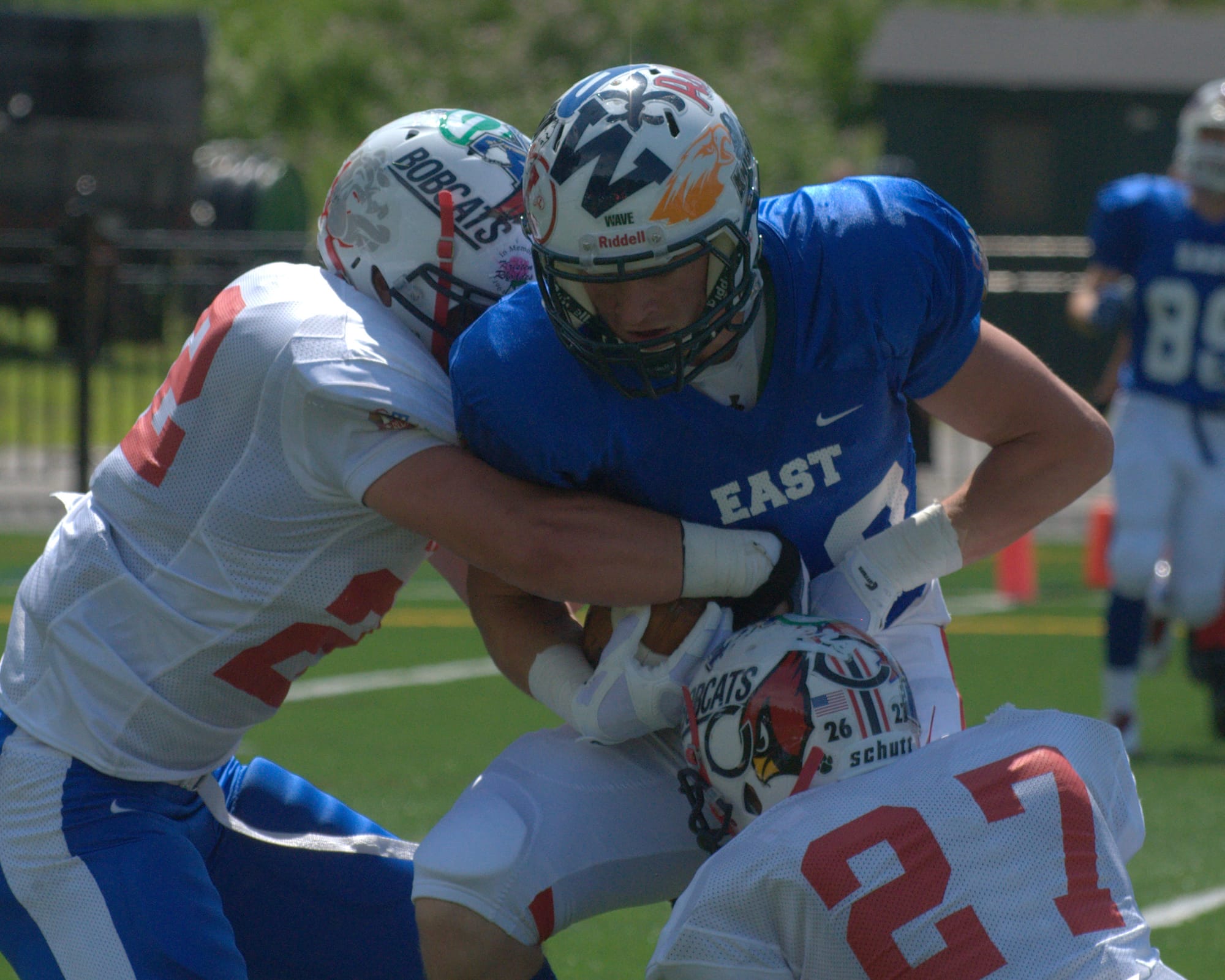 East's Tom McCullough tries to fight off West's Jared Kuehl, left, and John Thomas.