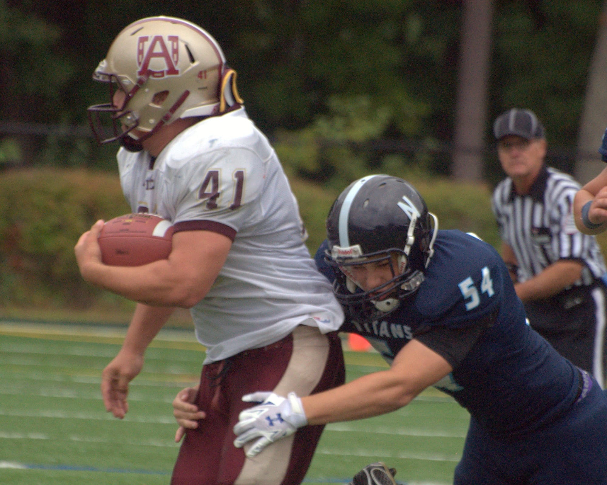 Alvirne's Ethan Rainville drags Nashua North's Phil Pereira for a few yards during Saturday's game.