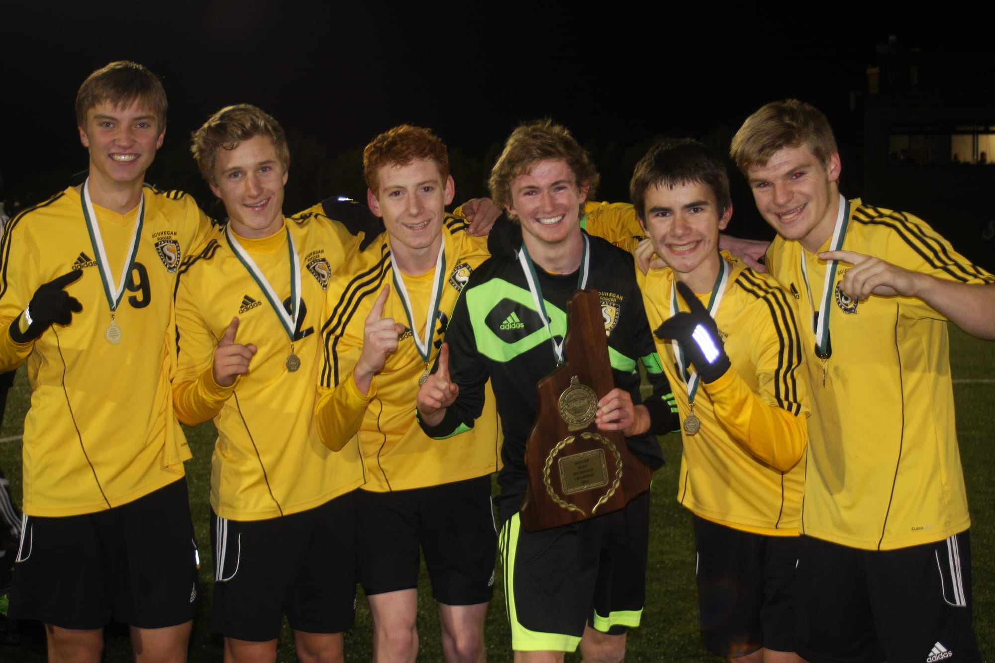 Souhegan boys soccer players pose with the Division II championship plaque after the Sabers defeated Oyster River on Saturday (Photo by Bill Dod).