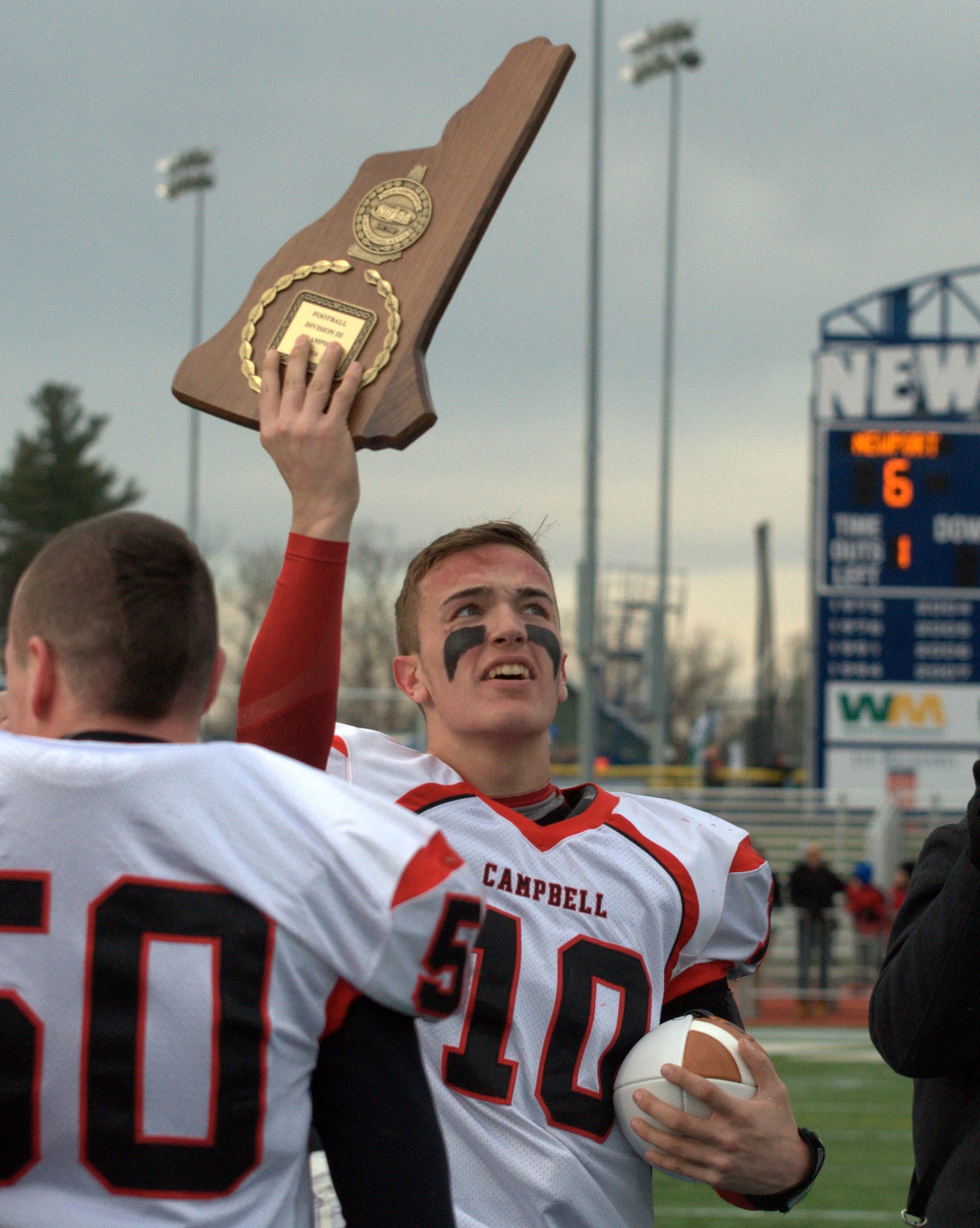 Campbell's Kyle Manning holds up the Division III championship plaque after the Cougars defeated Newport on Saturday.