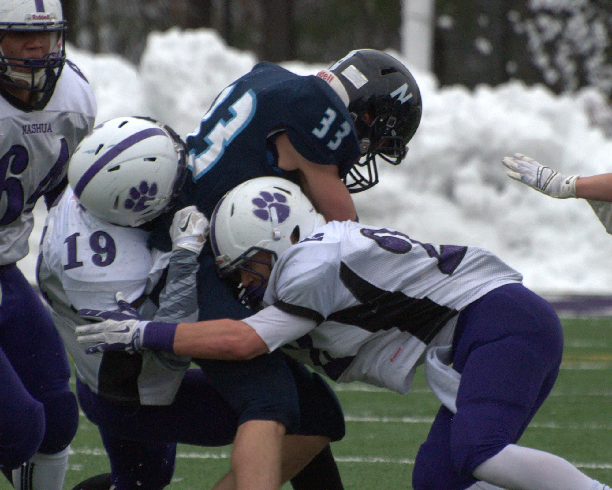 Nashua North's Max Fay is wrapped up by Nashua South's Jesse Clauss, elft, and Josh Perry.