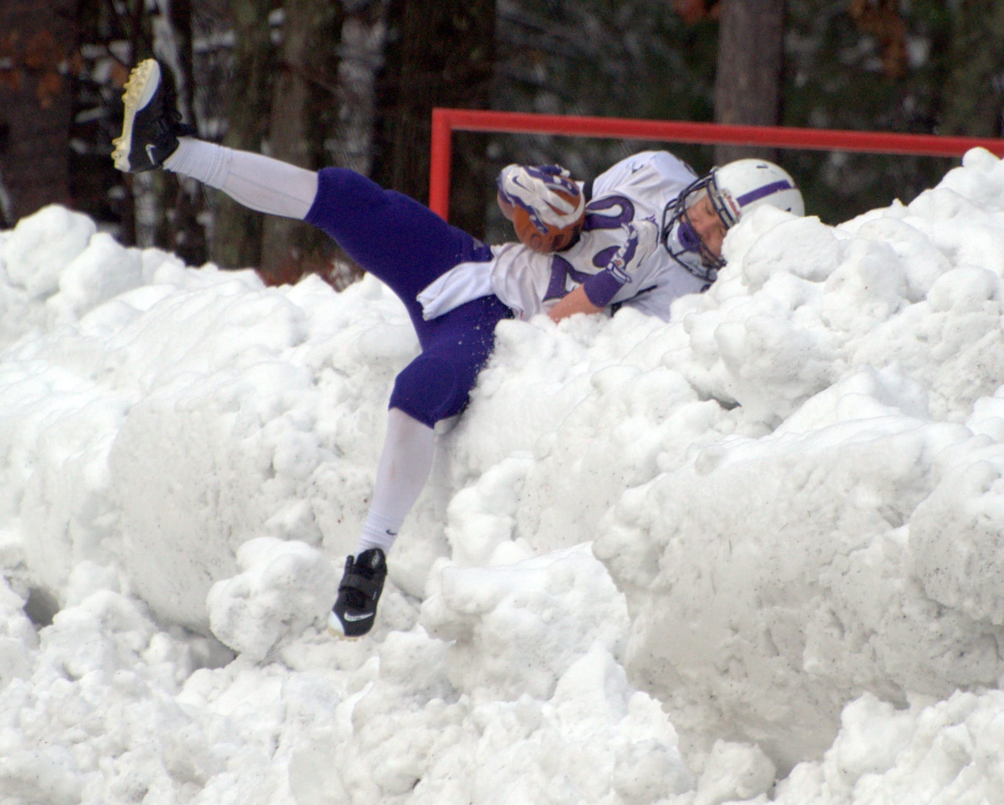 Nashua South's Josh Perry dives into a snowbank after scoring a touchdown during Thursday's game against Nashua North.