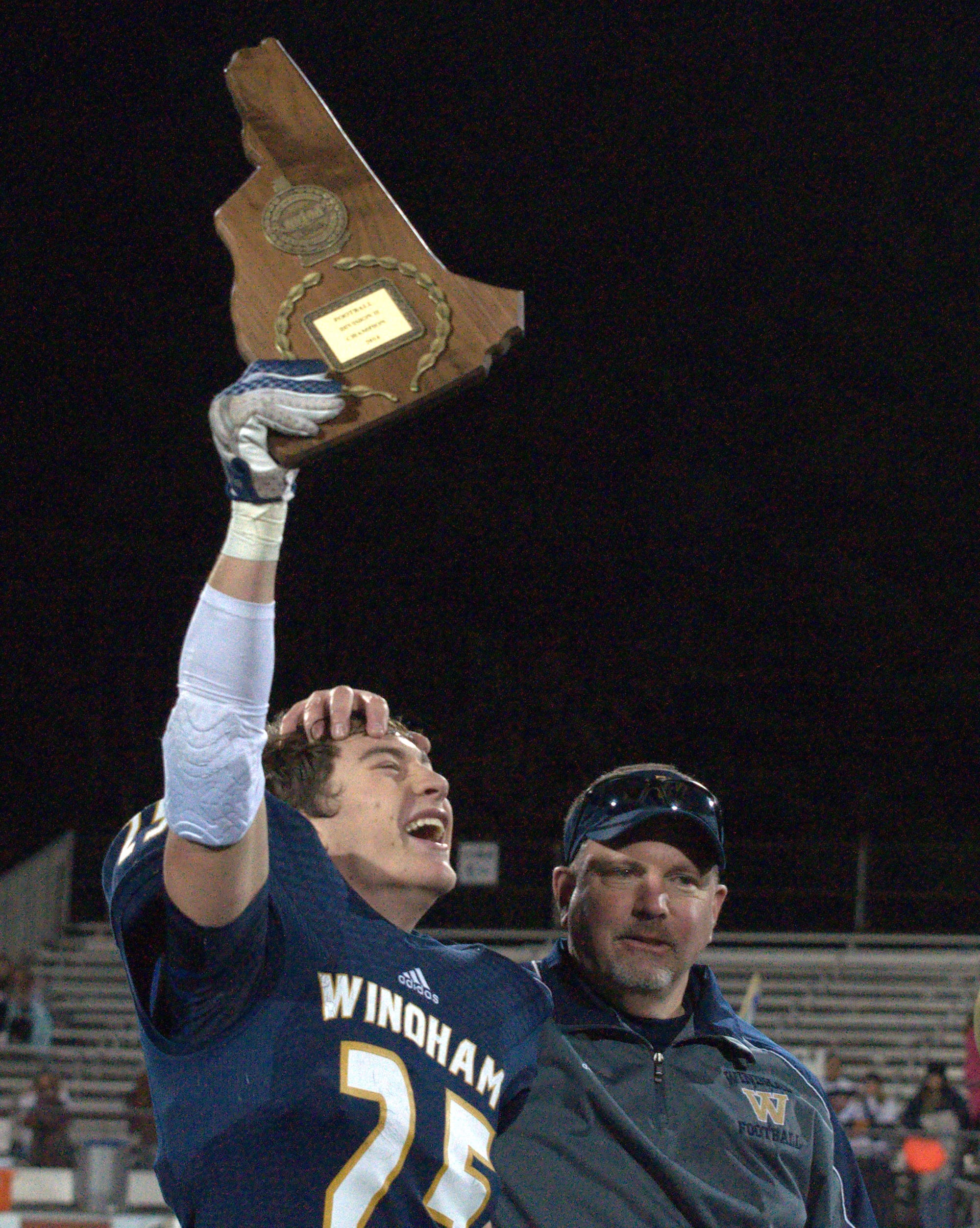Windham's Kellin Bail holds up the Division II championship plaque as he celebrates with coach Bill Raycraft after Saturday's win.