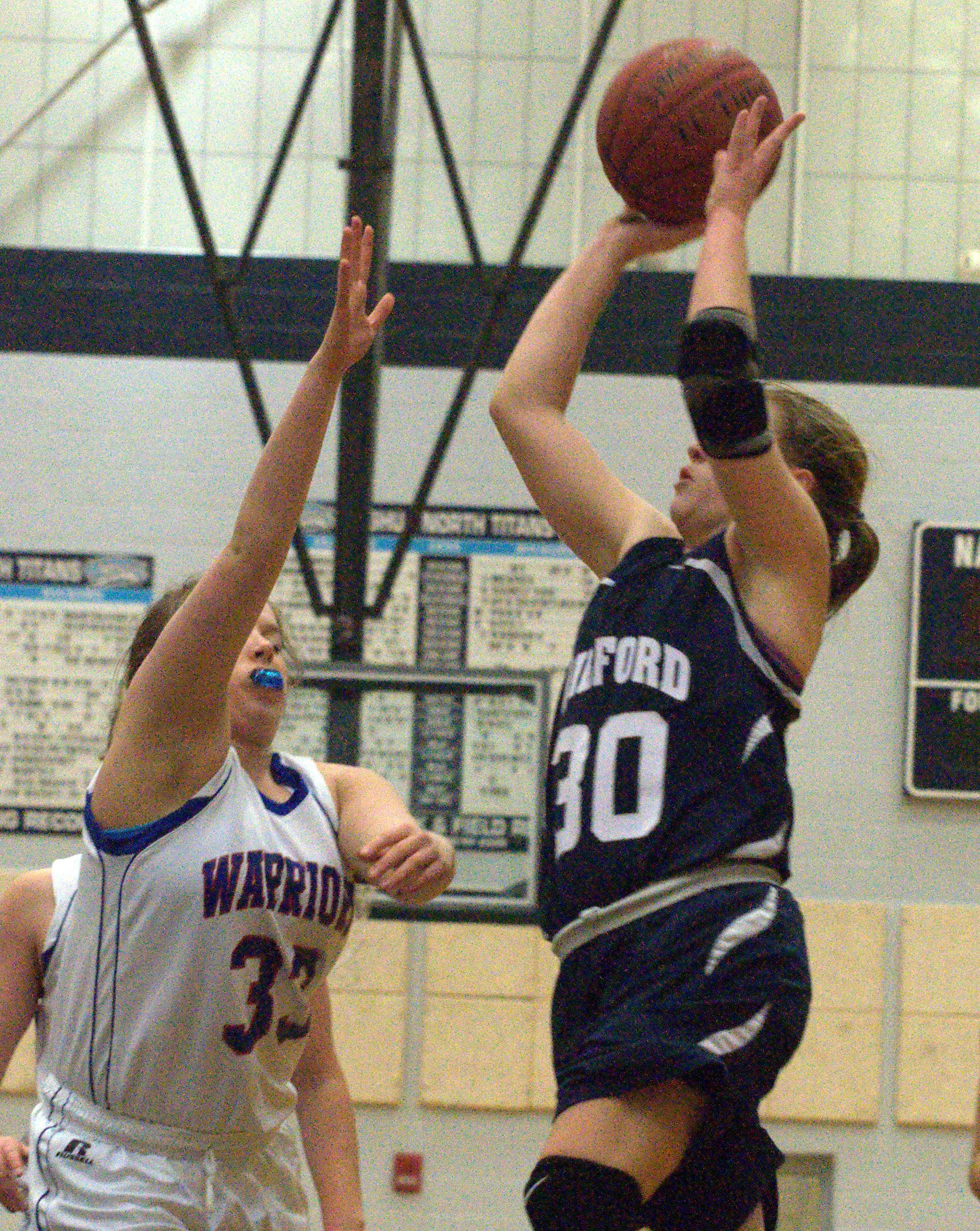 Milford's Erin McGuire drives to the basket as Winnacunnet's Sarah Dyer defends.