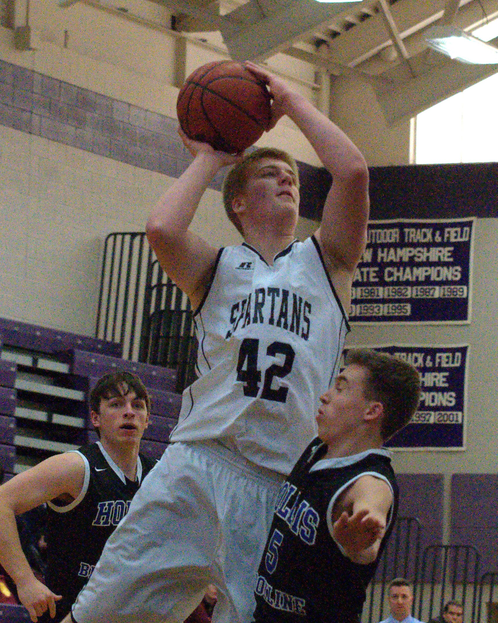 Hollis Brookline's Stephen Giaconia tries to draw a foul as Milford's Tom Simo puts up a shot.