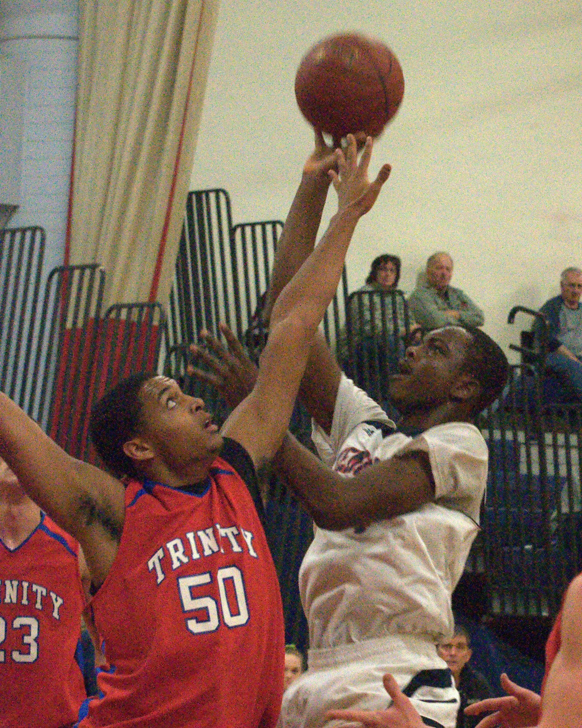 Trinity's Keanyon Lambert tries to block a shot by Manchester Memorial's Kabango Ngalakulondi during Saturday's game at the Queen City Invitational Tournament.