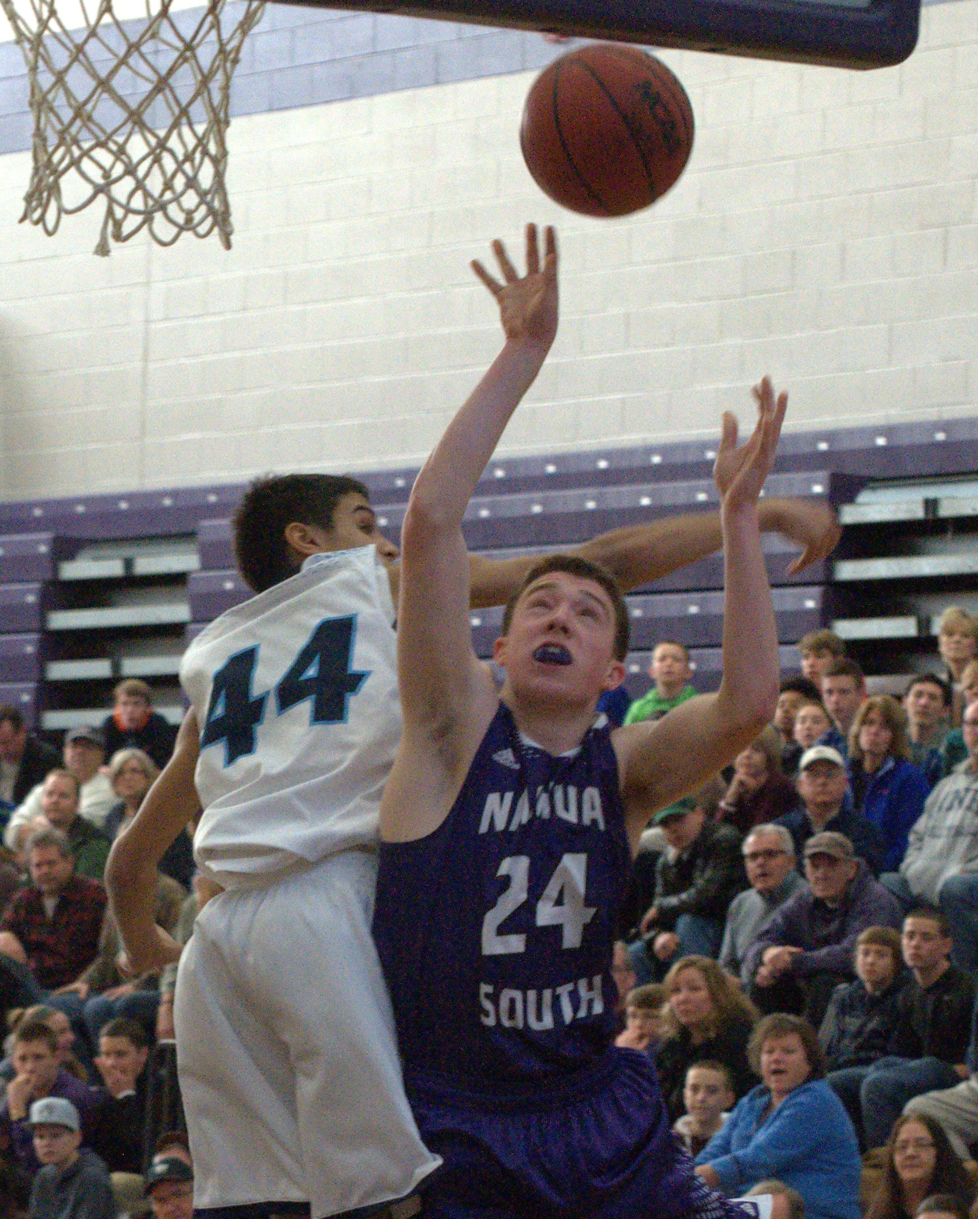 Nashua South's Ryan Penkala is fouled by Nashua North's Ronnie Silva.