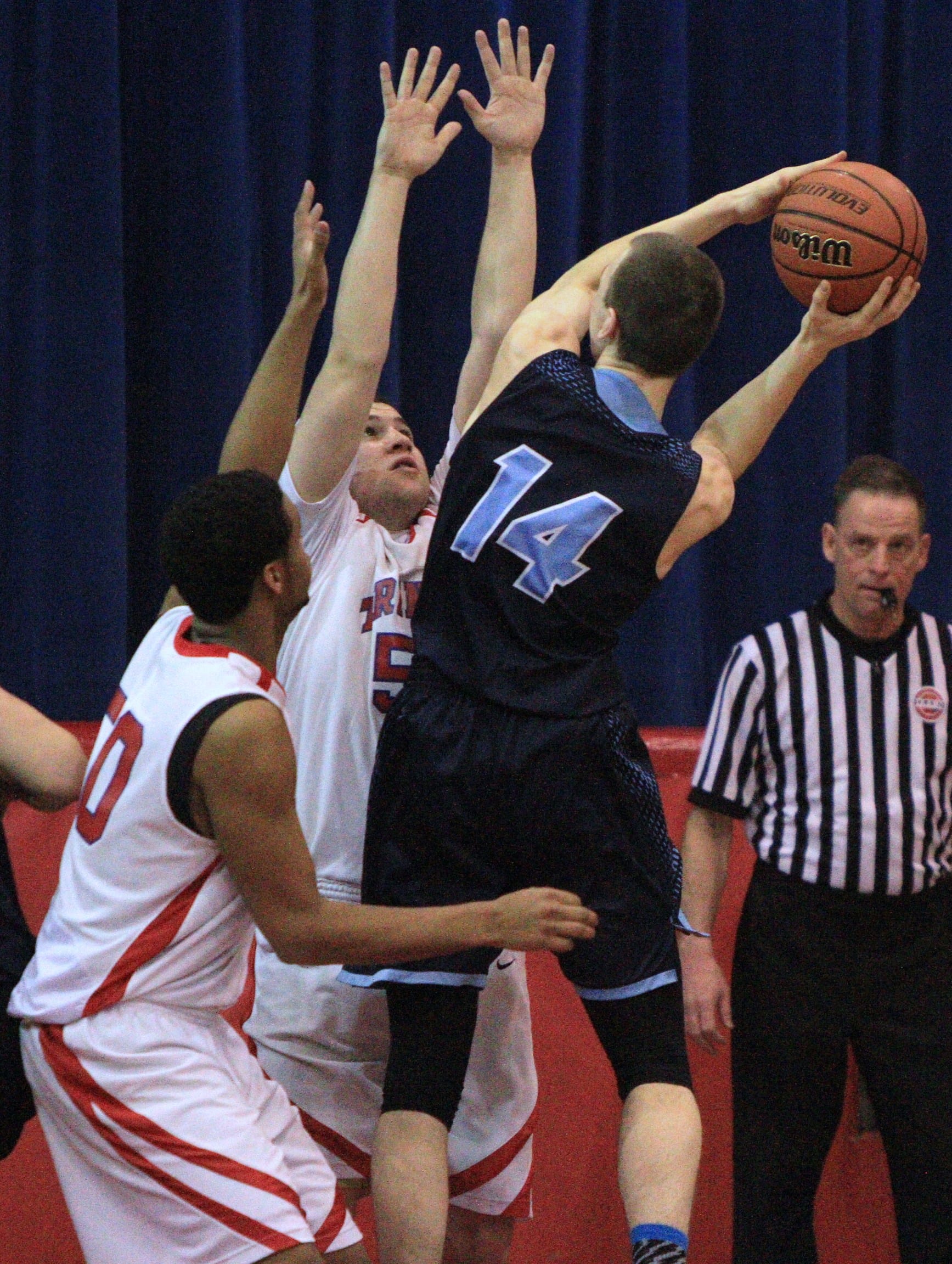 Trinity's Keanyon Lambert, left, and Connor Walsh defend Nashua North's Brennan Kastens at the basket during Saturday night's Division I quarterfinal in Manchester (Courtesy photo).