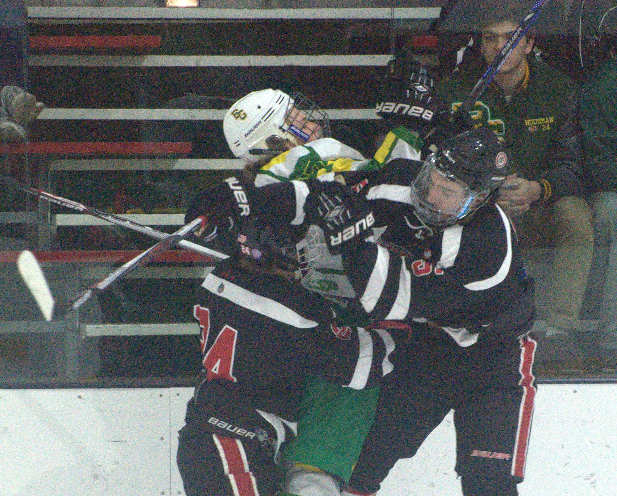 Bishop Guertin's Ryan Flynn takes a hit from Bedford's Jacob Rioux, left, and Nathaniel John.