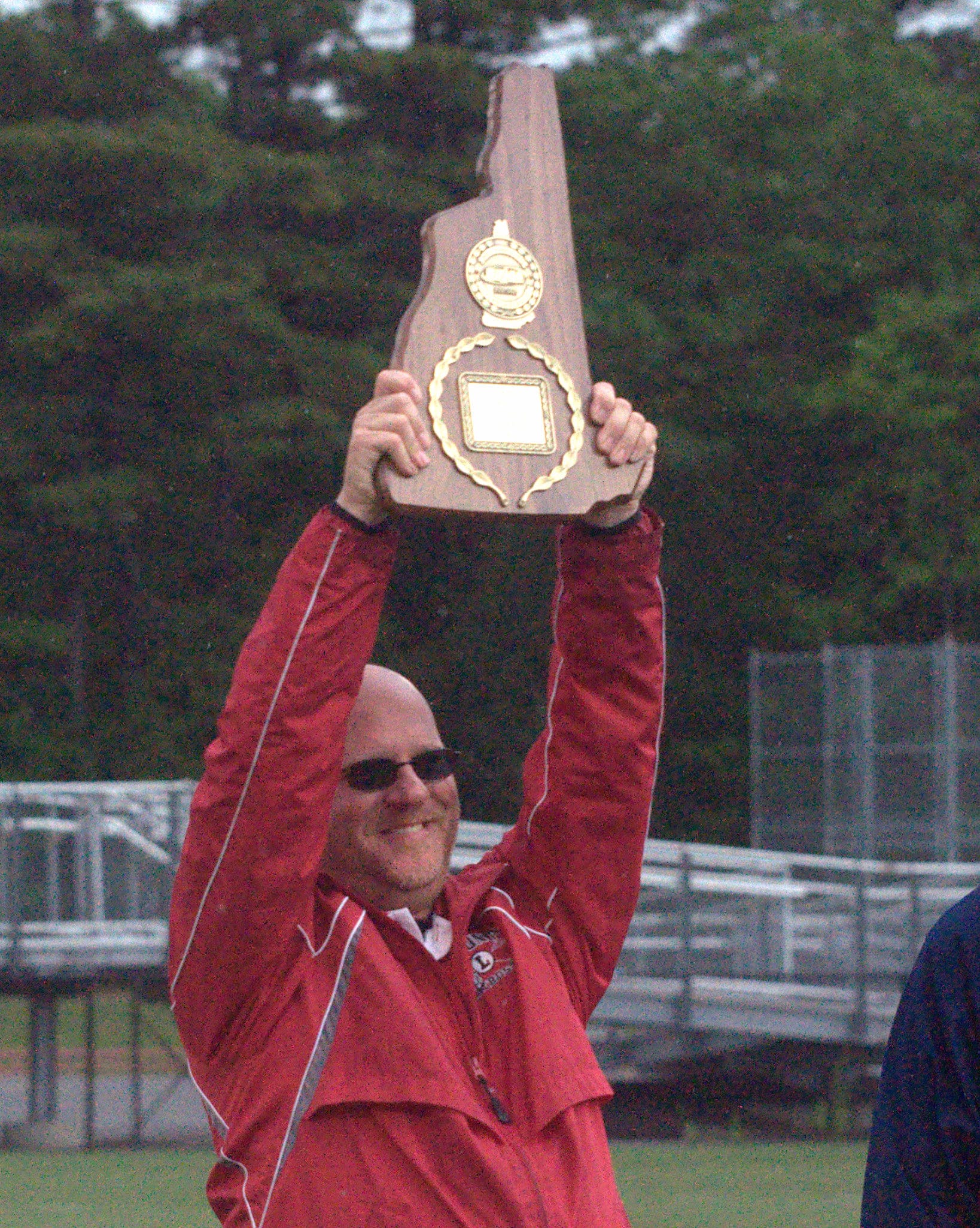 Laconia coach Andy Paronto holds up the Division III championship plaque.