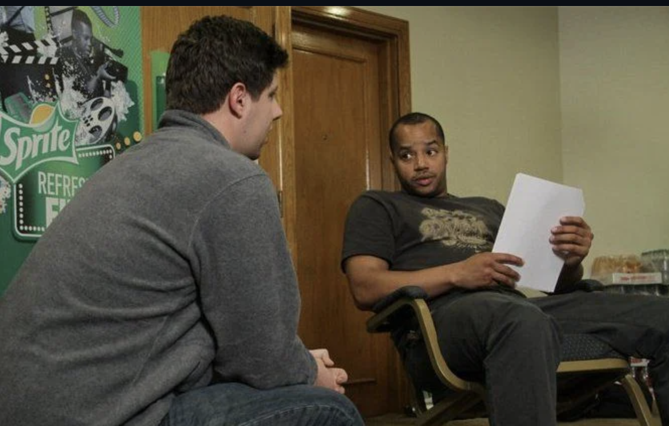 Post writer Philip Kimbrough, in a grey pullover, kneeling talking to Donald Faison of Scrubs fame
