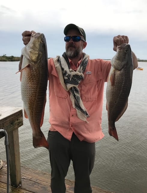 A proud fisherman displays two large Louisiana red drum.