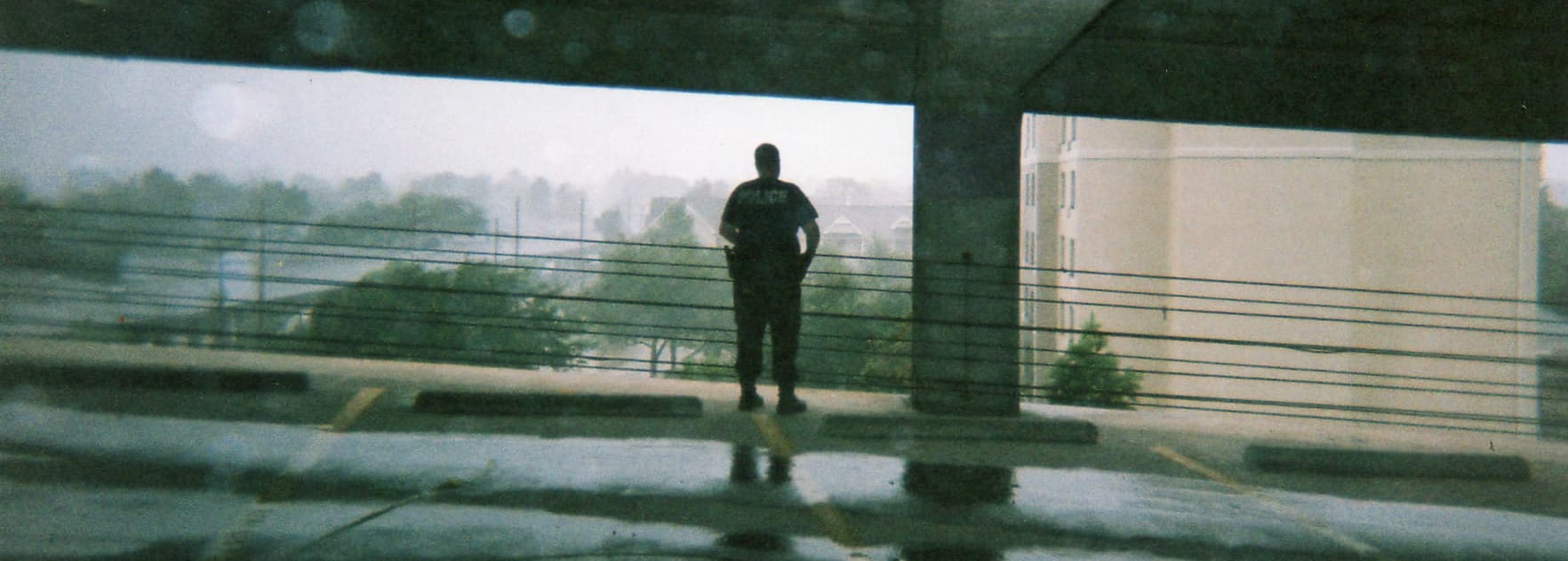 A police officer looks out at a Hurricane from the protection of a parking garage.