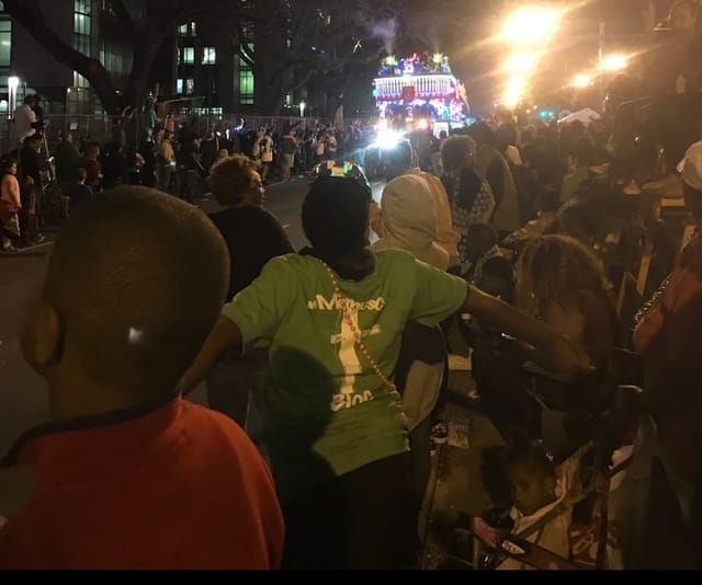 A lighted floated rolls down a crowded night street in New Orleans during Mardi Gras.
