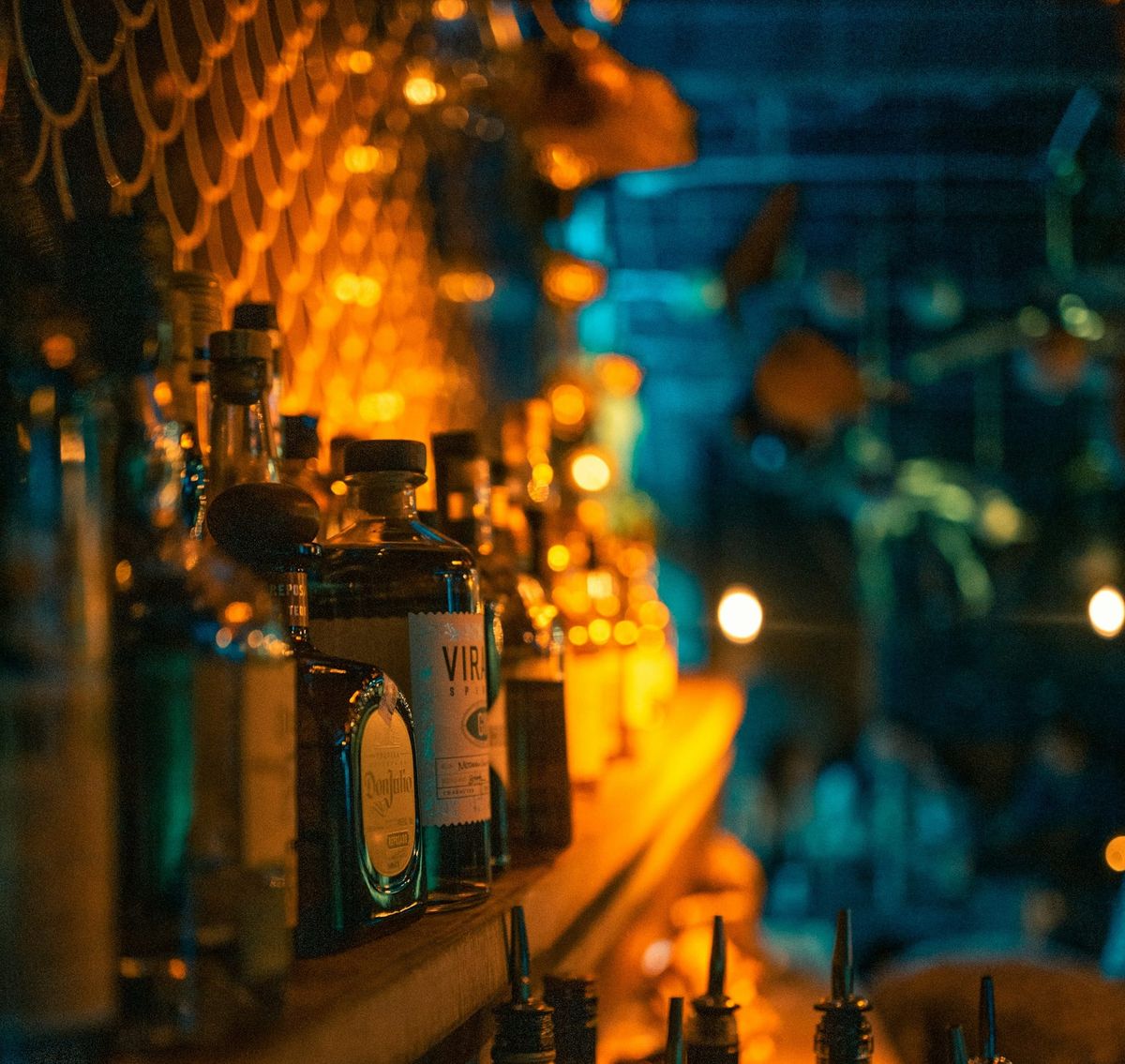 A dimly lit, sagging, shelf full of liquor bottles.